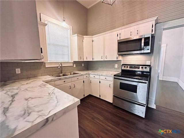 207 Schrimsher St, Yoakum, TX 77995 - kitchen featuring appliances with stainless steel finishes, backsplash, dark wood-style flooring, and white cabinetry