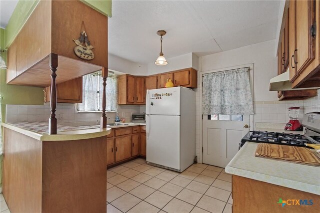 2080 Allison Rd, Martindale, TX 78655 - kitchen with freestanding refrigerator, range with gas stovetop, decorative backsplash, and brown cabinets