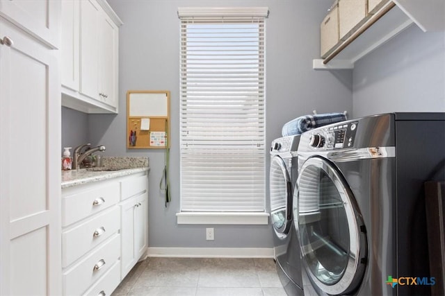 laundry room with washing machine and dryer, sink, light tile patterned floors, and cabinets