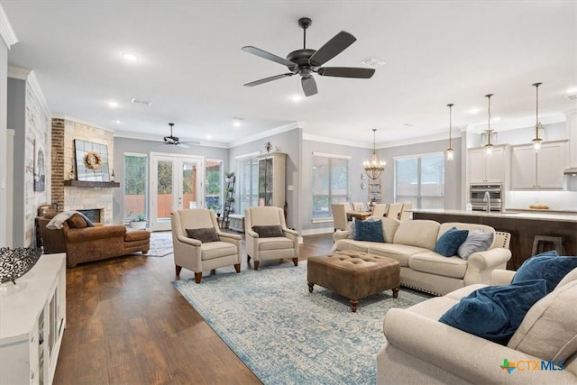 living room with a healthy amount of sunlight, a stone fireplace, ornamental molding, and dark wood-type flooring