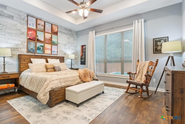 bedroom with a tray ceiling, ceiling fan, and wood-type flooring