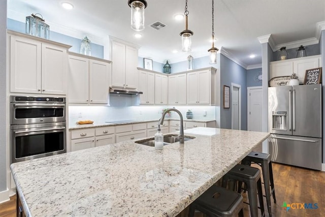 kitchen with sink, dark wood-type flooring, decorative light fixtures, a kitchen island with sink, and appliances with stainless steel finishes