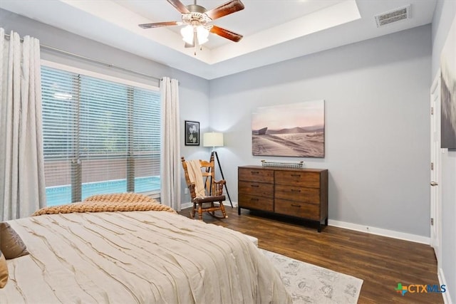 bedroom featuring a tray ceiling, ceiling fan, and dark wood-type flooring