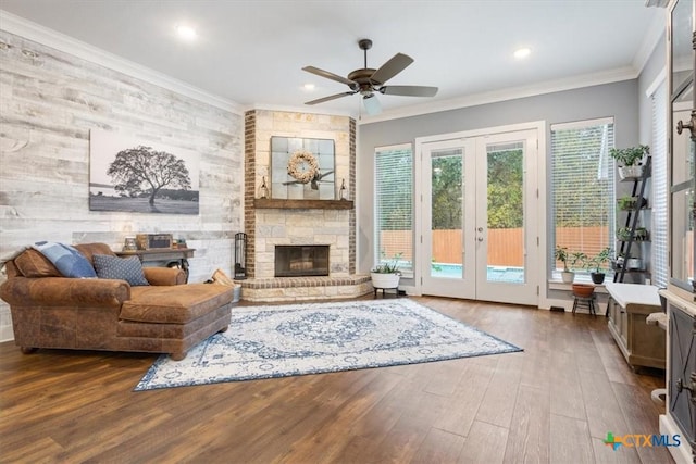 living room featuring ceiling fan, french doors, dark wood-type flooring, crown molding, and a fireplace