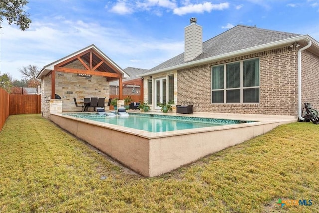 rear view of property with a fenced in pool, a lawn, and a patio