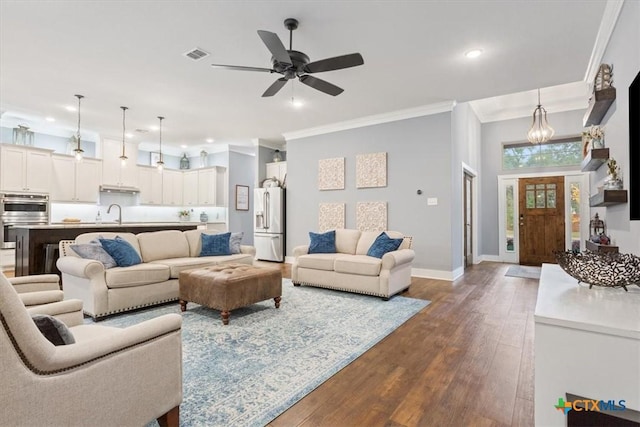 living room with crown molding, ceiling fan, dark wood-type flooring, and sink