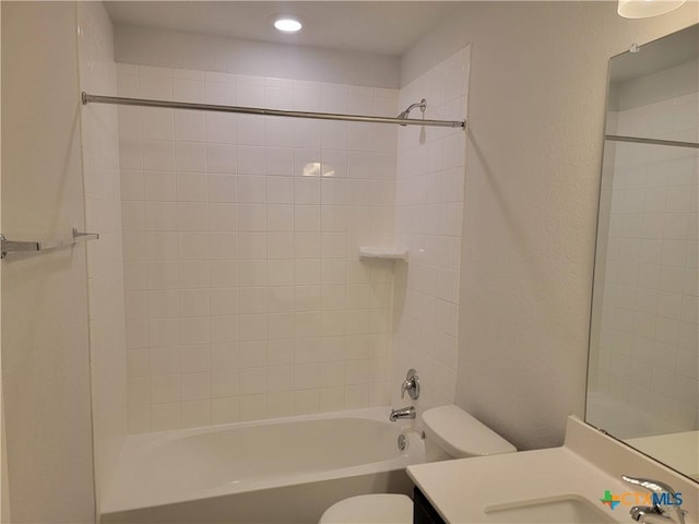 full bath featuring vanity, bathing tub / shower combination, toilet, and a textured wall