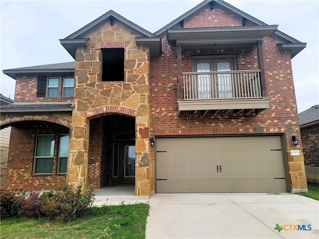 view of front of property with brick siding, stone siding, concrete driveway, and a balcony