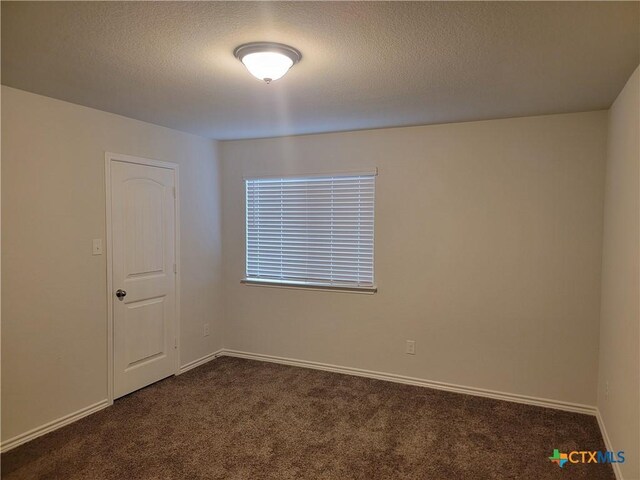 spare room with baseboards, dark carpet, and a textured ceiling