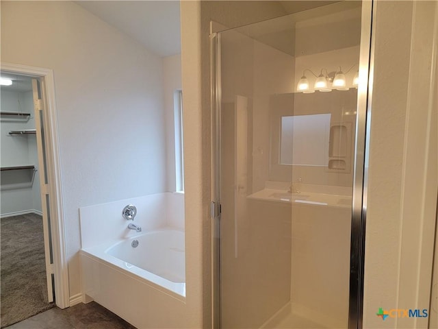 bathroom featuring a bath, a stall shower, and a spacious closet