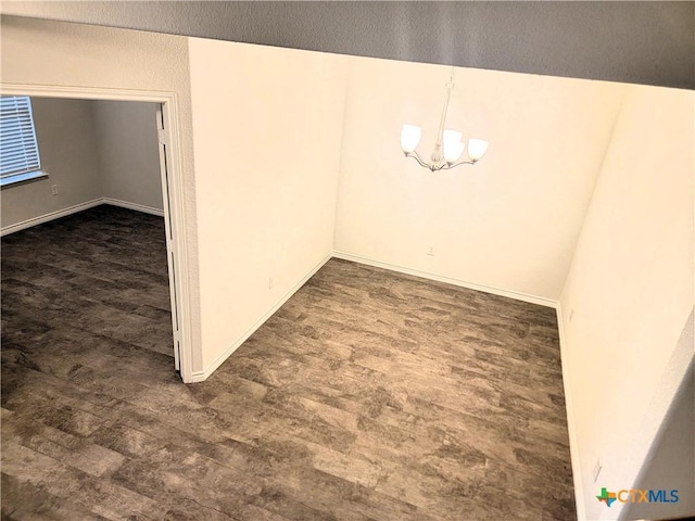 unfurnished dining area featuring dark wood-type flooring, baseboards, and a chandelier