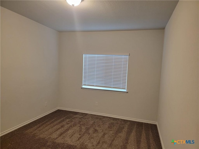 unfurnished room featuring a textured ceiling, baseboards, and dark colored carpet