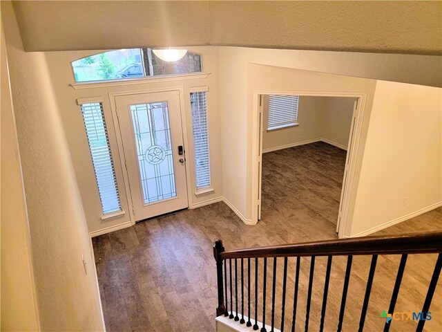 foyer entrance with baseboards, wood finished floors, and stairs