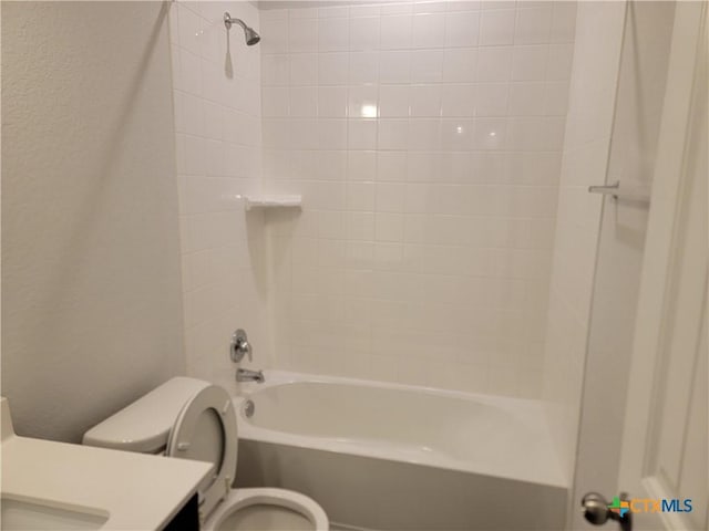 bathroom featuring vanity, toilet, shower / bathtub combination, and a textured wall