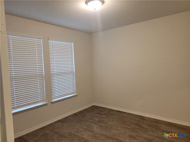 empty room with dark colored carpet and baseboards