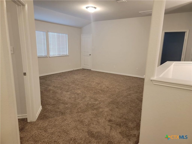 unfurnished room with visible vents, baseboards, carpet, and vaulted ceiling