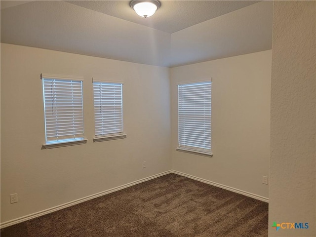 empty room with baseboards and dark carpet