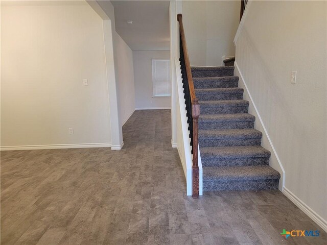 staircase featuring baseboards and wood finished floors