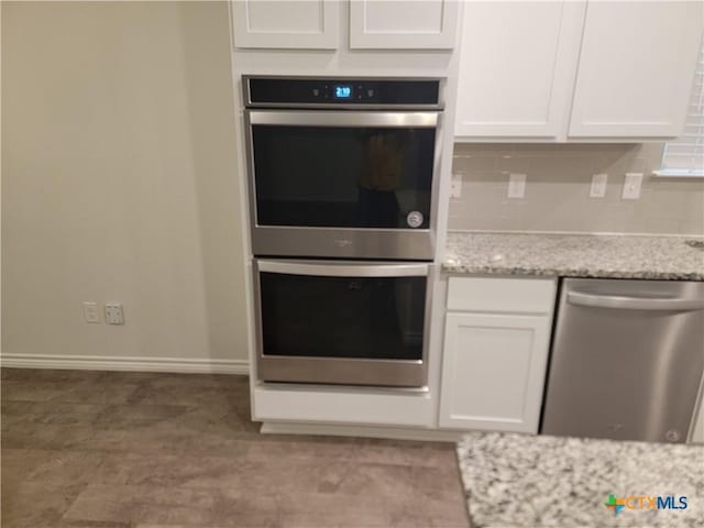 kitchen featuring backsplash, white cabinets, appliances with stainless steel finishes, and light stone counters