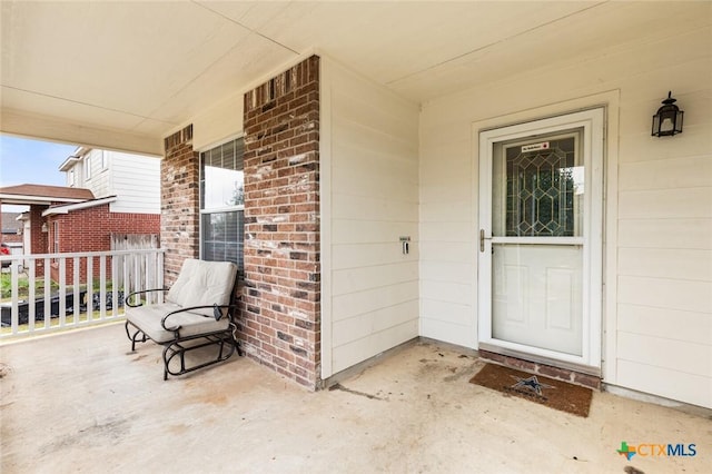 entrance to property featuring covered porch and brick siding