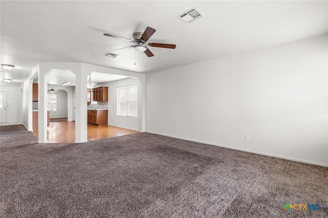 unfurnished living room featuring light carpet, ceiling fan, visible vents, and baseboards