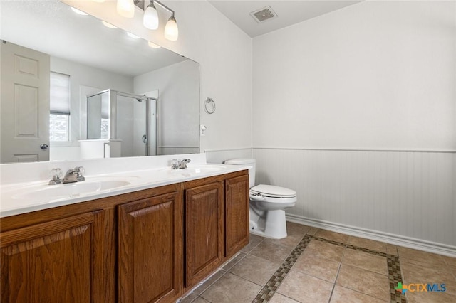 bathroom featuring double vanity, a stall shower, wainscoting, tile patterned flooring, and a sink