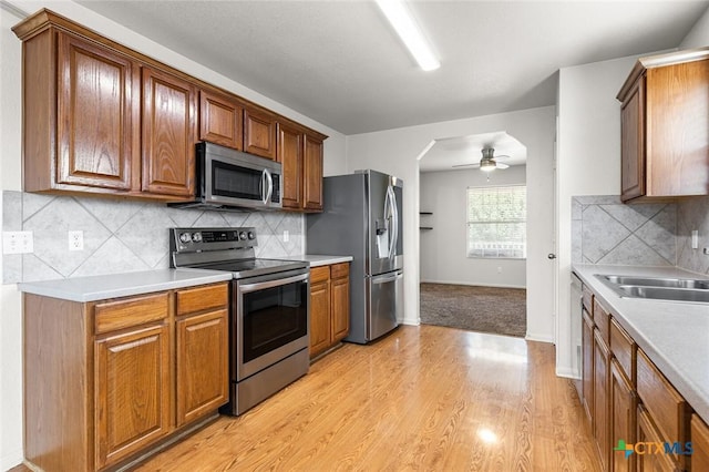 kitchen with brown cabinets, light wood-style floors, stainless steel appliances, and light countertops