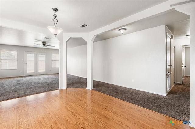 unfurnished room featuring carpet, visible vents, ceiling fan, and wood finished floors