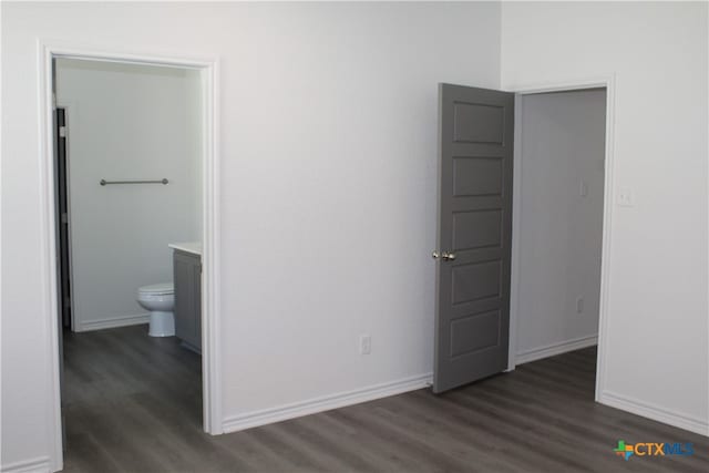 unfurnished bedroom featuring ensuite bathroom and dark hardwood / wood-style flooring