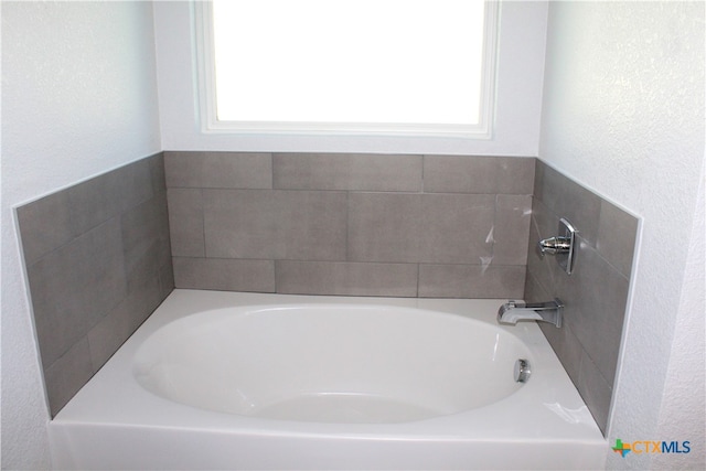 bathroom with a bathing tub and a healthy amount of sunlight