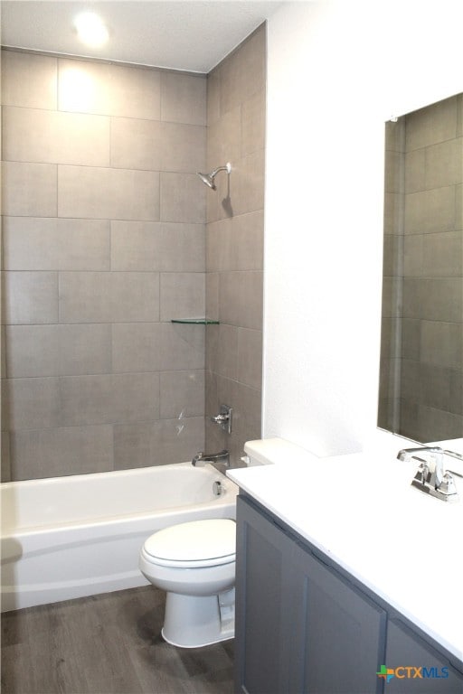 full bathroom with vanity, wood-type flooring, tiled shower / bath combo, and toilet