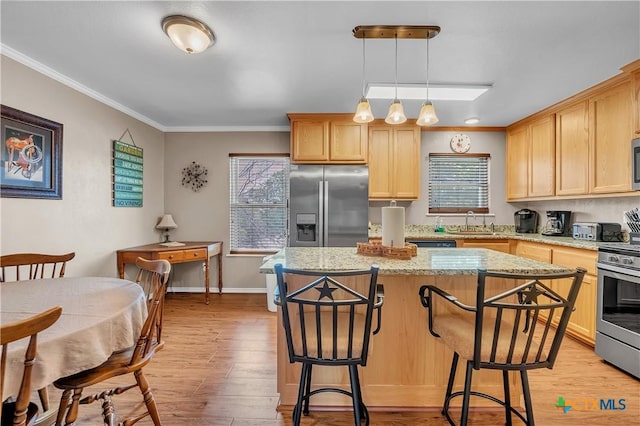 kitchen featuring stainless steel appliances, light brown cabinetry, light wood-type flooring, a breakfast bar, and ornamental molding
