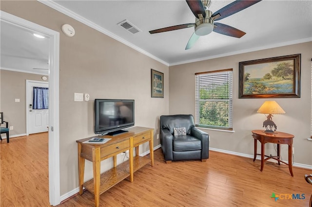 living area featuring visible vents, light wood finished floors, baseboards, and ornamental molding