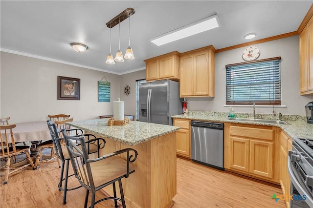 kitchen with light brown cabinets, a sink, light wood-style floors, appliances with stainless steel finishes, and ornamental molding