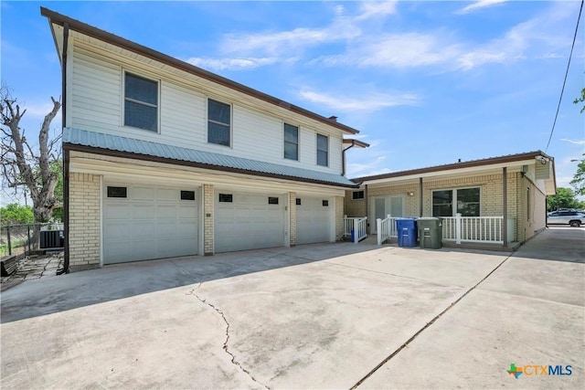 traditional-style home featuring fence, central AC, concrete driveway, brick siding, and a garage