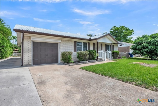 ranch-style home with concrete driveway, an attached garage, brick siding, a front yard, and metal roof