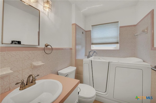 bathroom featuring tile walls, a garden tub, a sink, and toilet