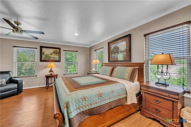 bedroom featuring light wood-style flooring, crown molding, and baseboards