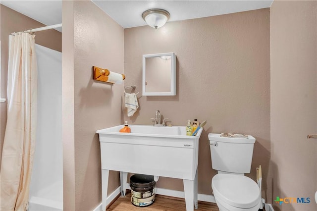 1009 E Robertson Ave, Copperas Cove, TX 76522 - full bath featuring toilet, wood finished floors, a shower with curtain, a textured wall, and baseboards