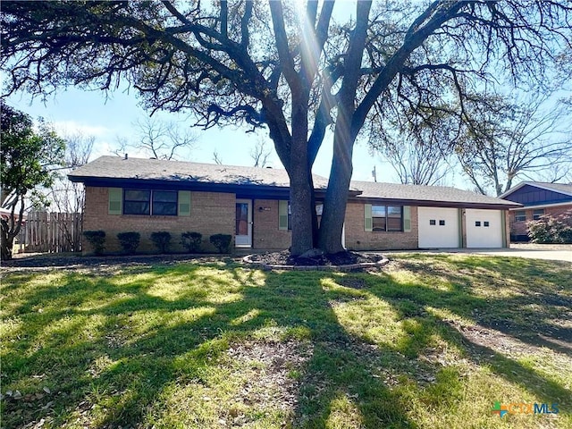 ranch-style house featuring a garage, brick siding, a front lawn, and fence