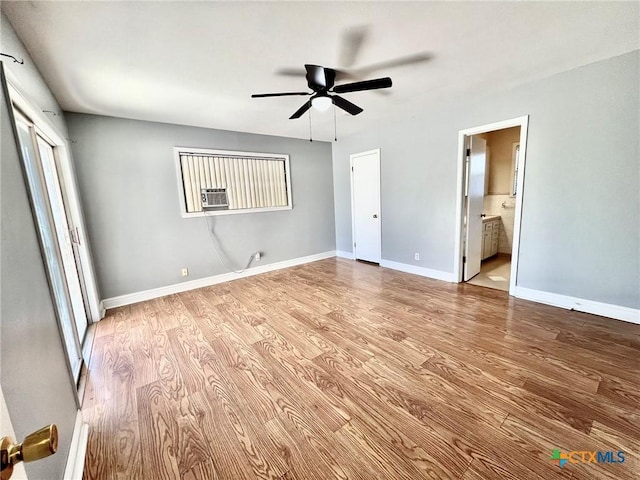 unfurnished bedroom with baseboards, a ceiling fan, connected bathroom, wood finished floors, and cooling unit