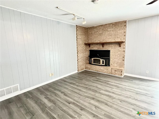 unfurnished living room with visible vents, a fireplace, baseboards, and wood finished floors