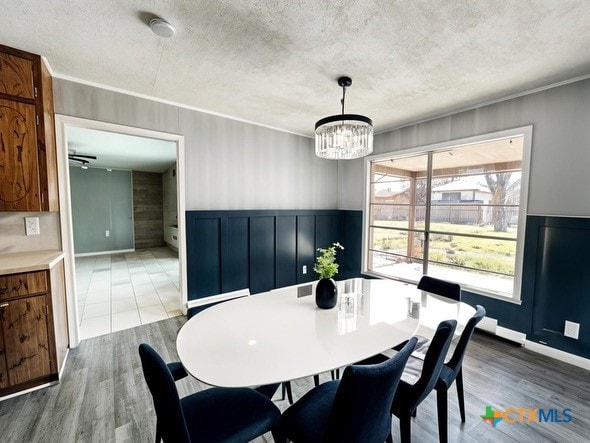 dining room with wood finished floors, a textured ceiling, and a notable chandelier
