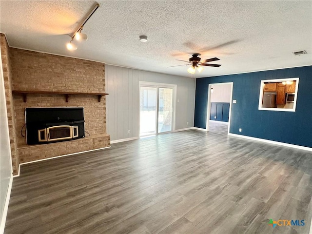 unfurnished living room featuring wood finished floors, a textured ceiling, ceiling fan, baseboards, and visible vents