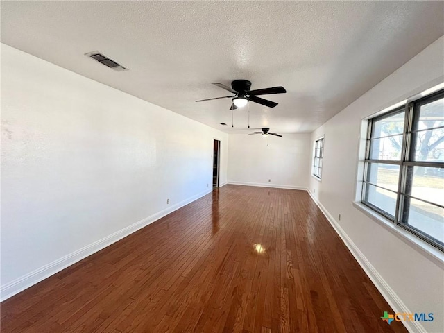 unfurnished living room with dark wood-style floors, visible vents, ceiling fan, a textured ceiling, and baseboards