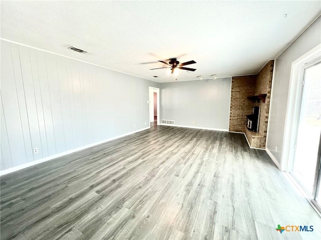 unfurnished living room with a large fireplace, wood finished floors, and visible vents