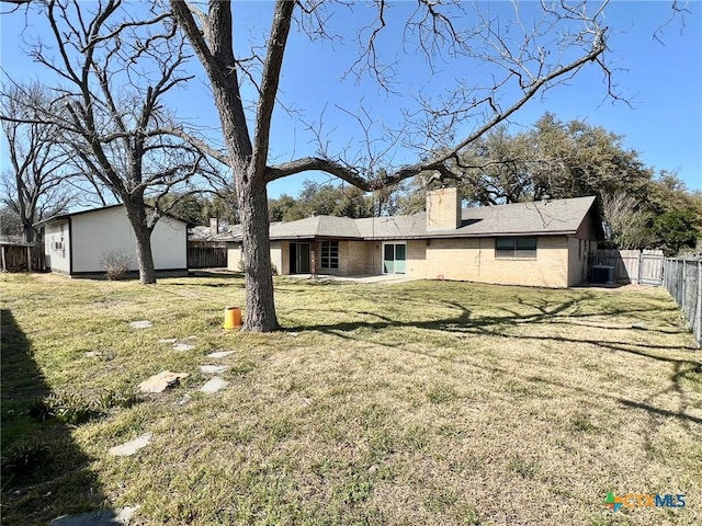 back of property featuring central AC unit, a fenced backyard, brick siding, a yard, and a chimney