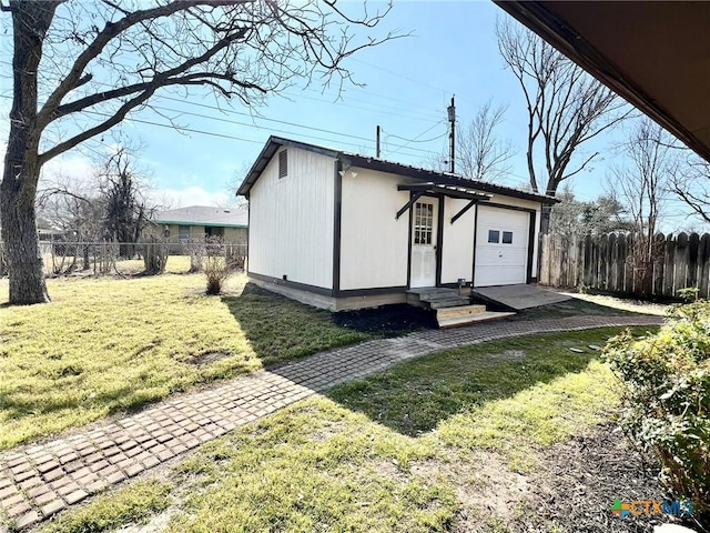 view of outdoor structure with fence, driveway, and entry steps