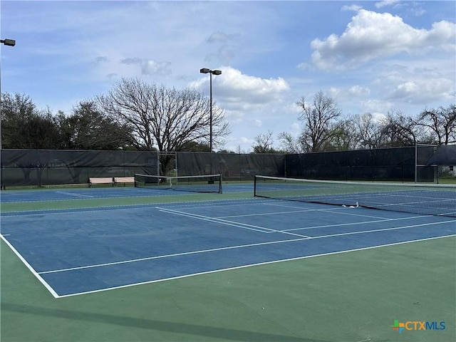 view of tennis court featuring fence and community basketball court