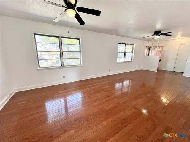 empty room featuring wood-type flooring, ceiling fan, a textured ceiling, and baseboards